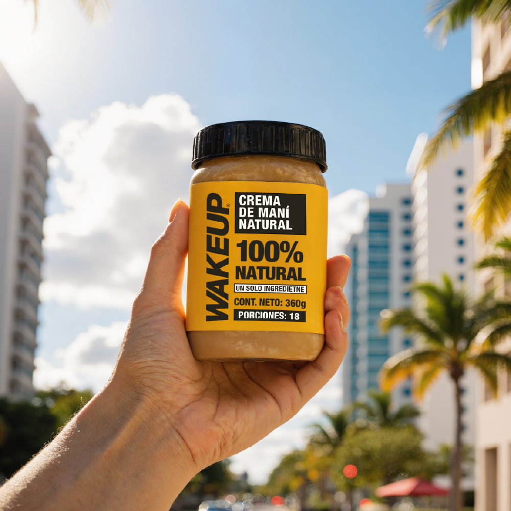 Crema WAKEUP 360g sostenida frente a palmeras, energía natural para llevar