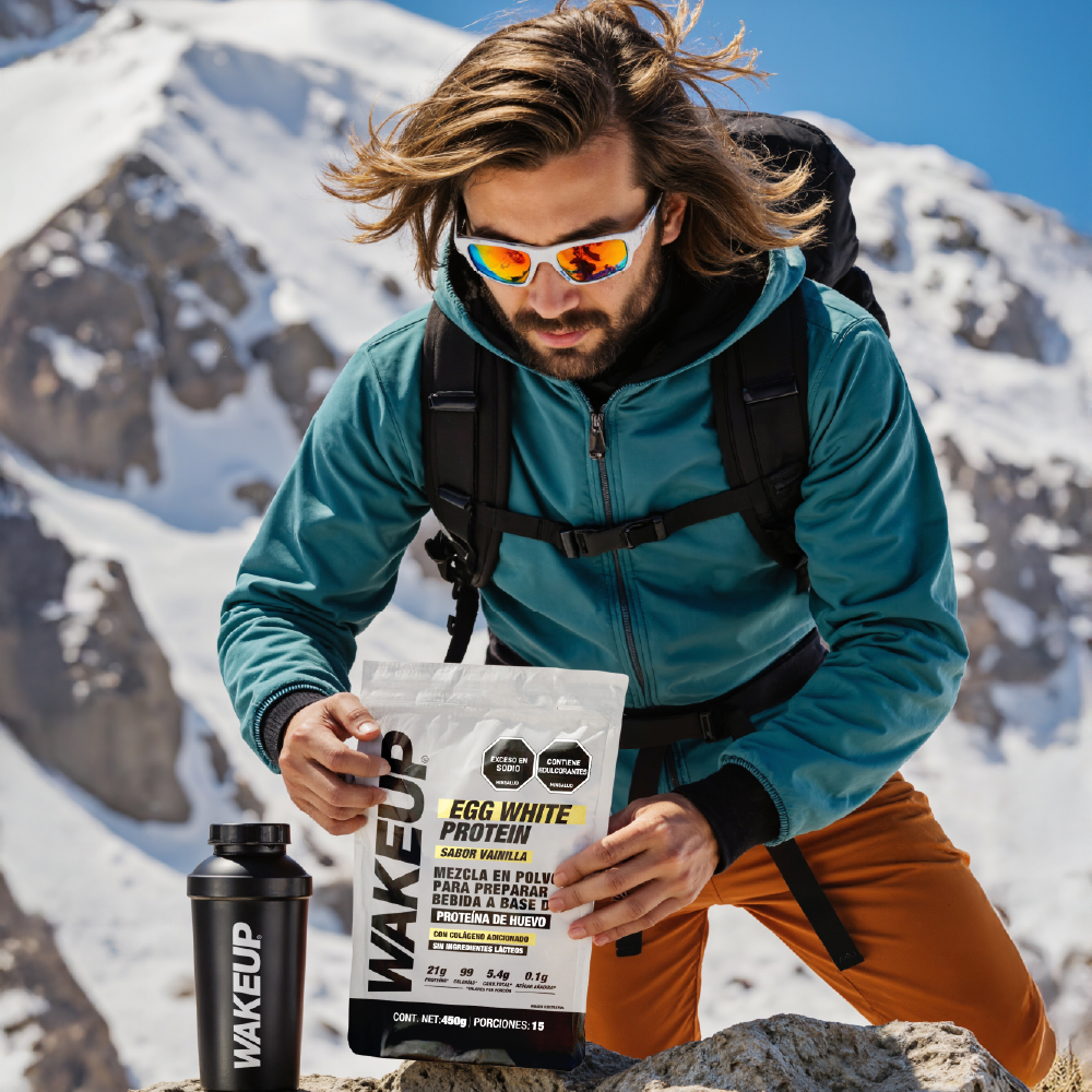 Hombre en montaña nevada sosteniendo proteína WAKEUP 450g sabor vainilla